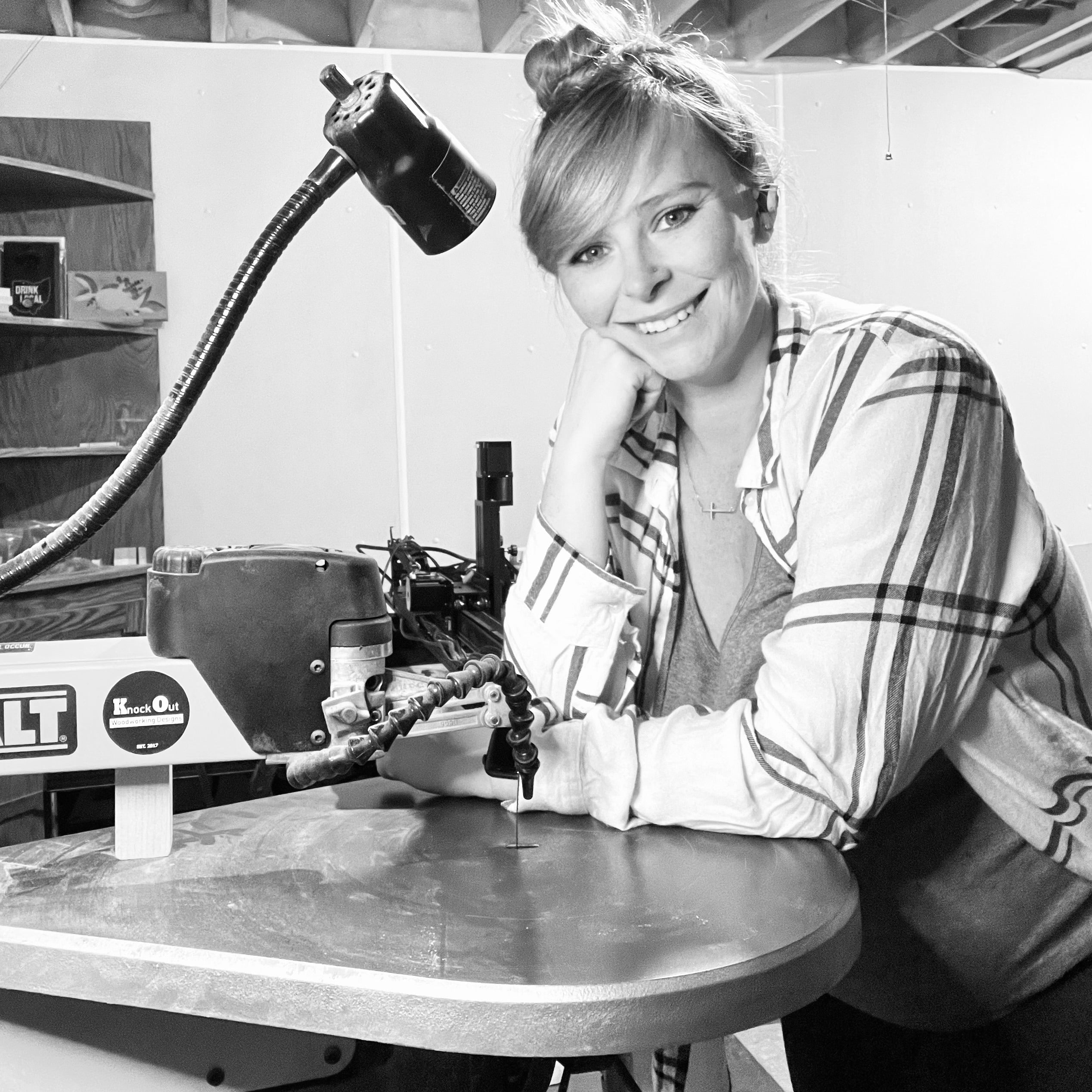 Person sitting at a scroll saw with equipment in a workshop setting